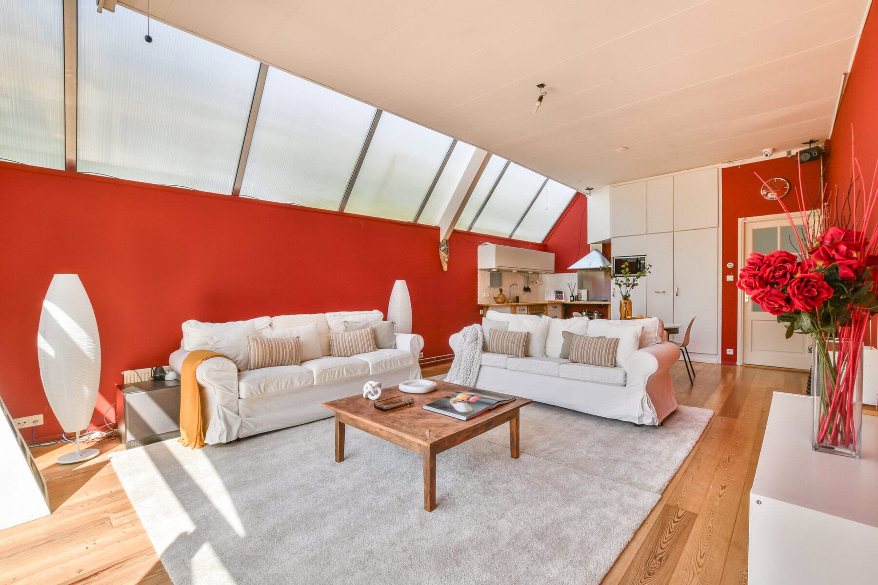 Bright living room with white sofas and red accent wall in Amsterdam property.