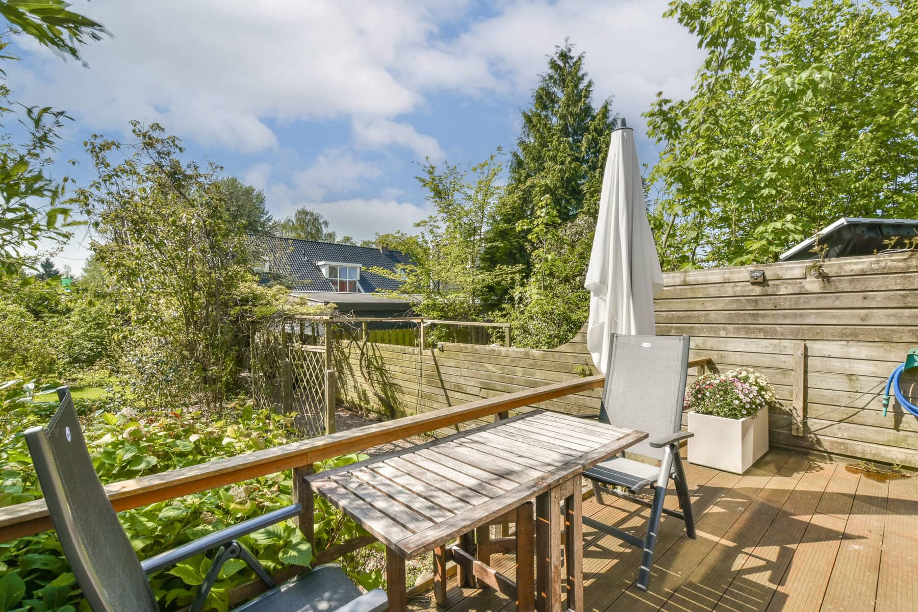 Outdoor seating area in a lush Amsterdam garden with table, chairs, and umbrella.