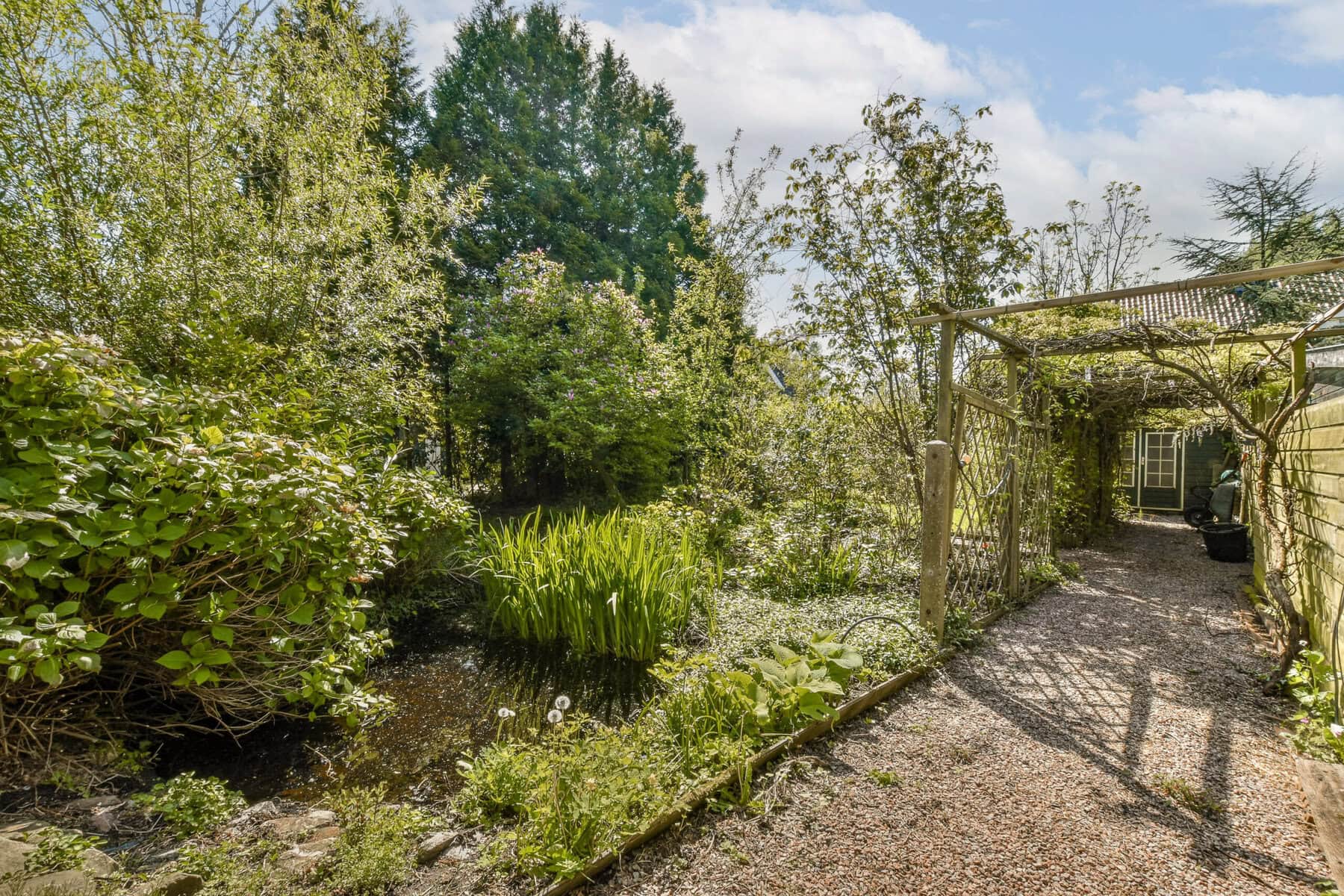 Garden view at Sloterweg 1257, Amsterdam with lush greenery and a gravel pathway.