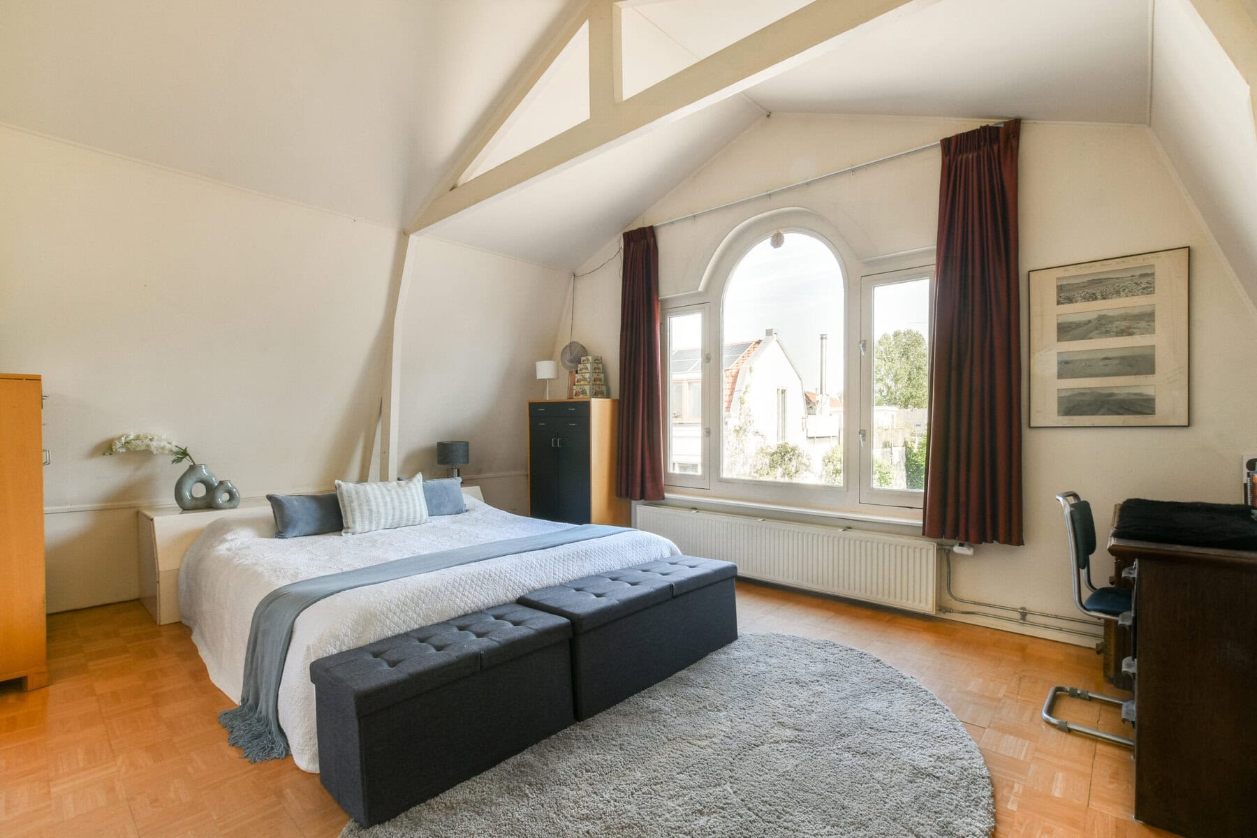 Bright bedroom with large window and sloped ceiling in Amsterdam property.